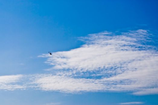 Rotary-wing aircraft in the blue cloud sky