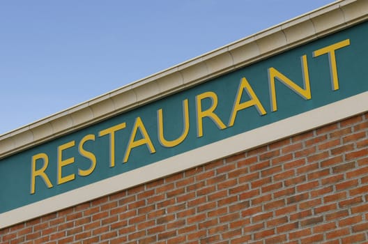 restaurant sign on a facade against a blue sky