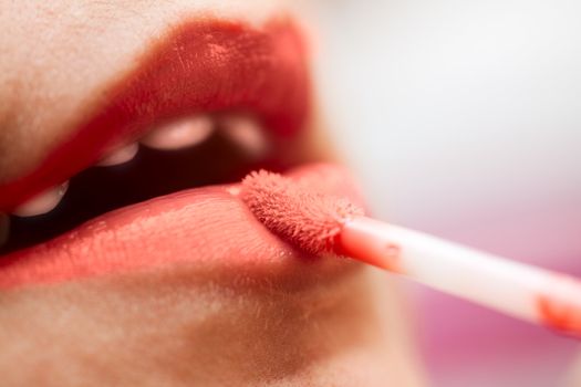 Close-up of a woman lips applying red lipstick.