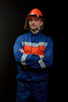 The worker in overalls and a helmet on a black background 