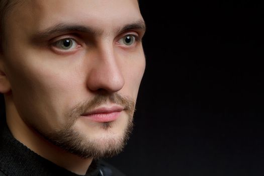 face of the young unshaven man in a black background