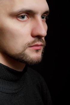 face of the young unshaven man in a black background