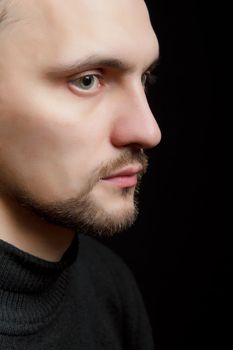 face of the young unshaven man in a black background
