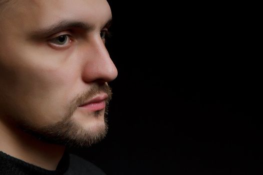 face of the young unshaven man in a black background