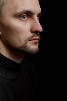 face of the young unshaven man in a black background