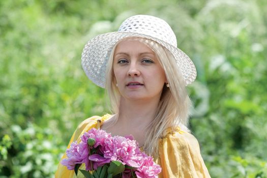 woman in a hat with flowers in the garden

