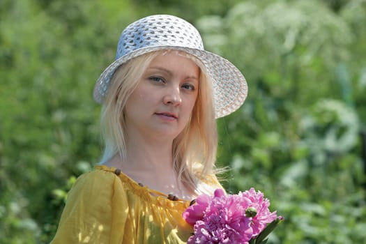 woman in a hat with flowers in the garden

