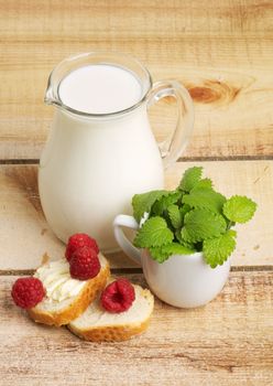 Healthy Breakfast with Jug of Milk, Raspberries, Mint Leafs and Toasts on Wooden background