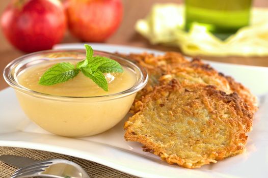 Apple sauce with potato fritters (Selective Focus, Focus on the front of the mint leaf on the apple sauce and half into the first fritter)