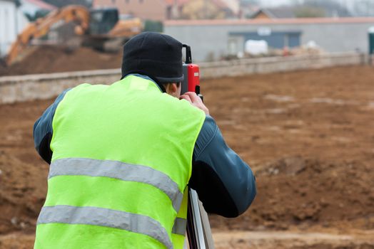 Building surveyor taking measurements on a construction site