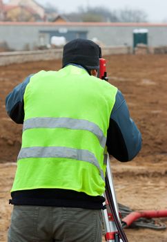 Building surveyor taking measurements on a construction site