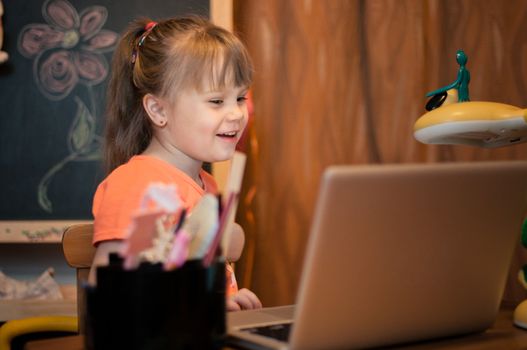 Young girl laughing with laptop in her small room