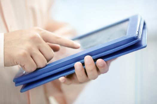 Hands of man in pink shirt using tablet PC indoors