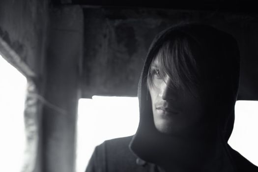 Horizontal photo of the criminal man with hood on his head in the dark interior. Shallow depth of field for movie effect