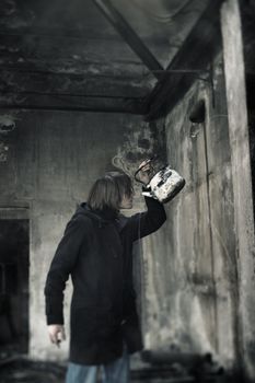 Single man indoors drinking water from the kettle in the dirty interior. Shallow depth of field due to the tilt lens for the movie effect