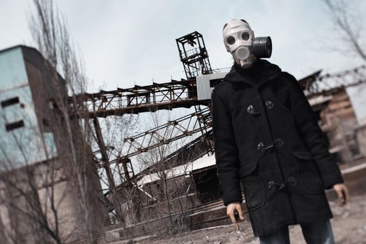 Man in gas mask standing at the factory after doomsday