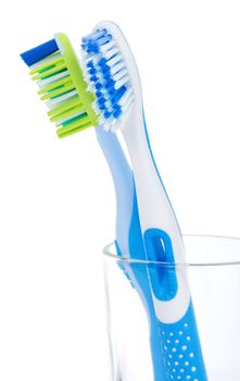 close-up two tooth brushes in glass, isolated on white