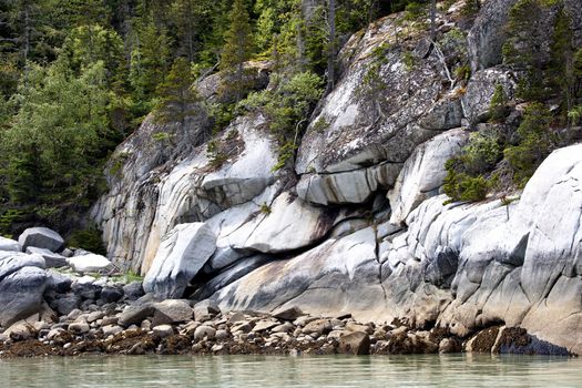 Rocks and trees create colorful screen at water's edge.