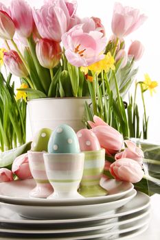 Easter eggs in cups with spring flowers on white background