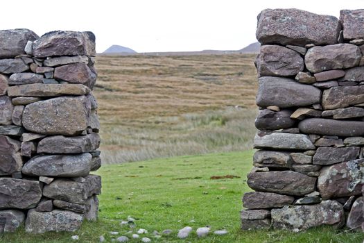 passage through stone wall with grazing land in background