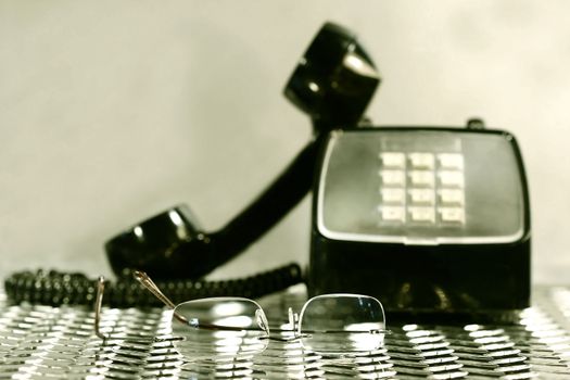 Black vintage telephone with a pair of reading glasses