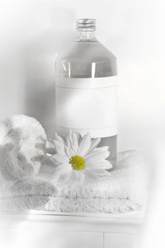 Bottle of linen water with towels and flower on cabinet