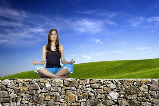 Woman making Yoga exercises in top of a stone wall