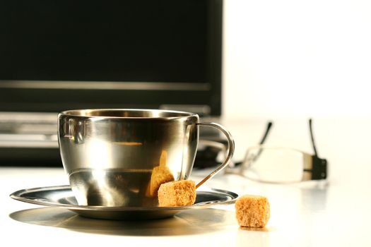 Stainless steel coffee cup with laptop in background