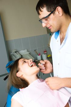 portrait of a young dentist examining the patient in his office