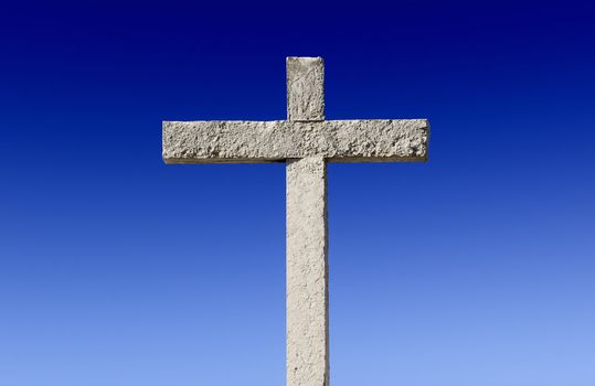 Religious stone cross on a beautiful blue sky