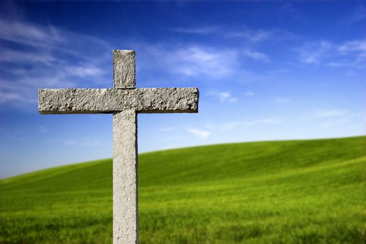 Religious stone cross on a beautiful green hill