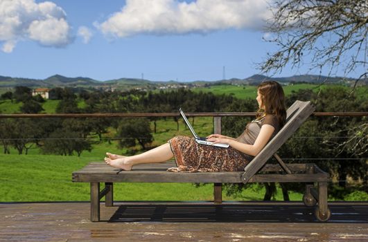 Woman enjoying a beautiful day with a laptop on her home-field