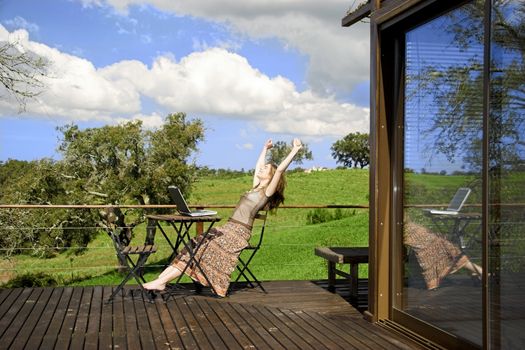 Woman enjoying a beautiful day with a laptop on her home-field