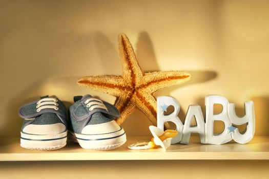 Baby shoes place on a shelf with baby pacifier, starfish etc..