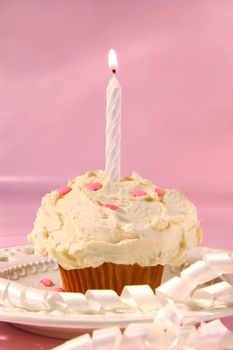 Little cupcake with candle on pink background