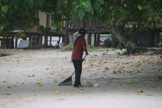 woman is cleaning the beach at koh chang island thailand 