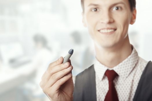 Smiling businessman holding a pen at his office