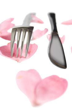 fork and knife isolated with rose petals for concept on romantic dining