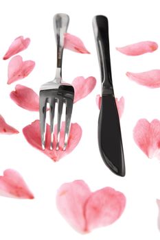 fork and knife isolated with rose petals for concept on romantic dining