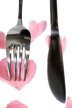 fork and knife isolated with rose petals for concept on romantic dining