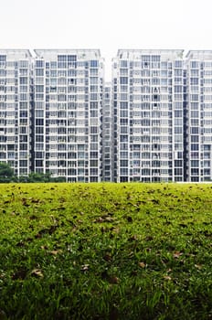 condominium housing with green grass field foreground.
