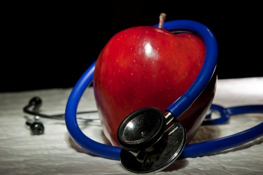 An zoomed apple surrounded by blue medical stethoscope