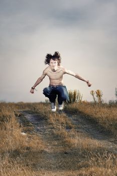 Angry topless muscular man outdoors jumping. Artistic colors added