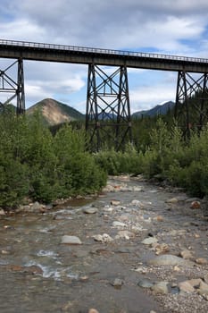 Bridge framed against blue cloudy sky and set in green environment.