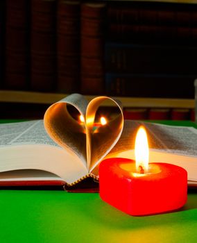 Open book laying on the table with burning candle