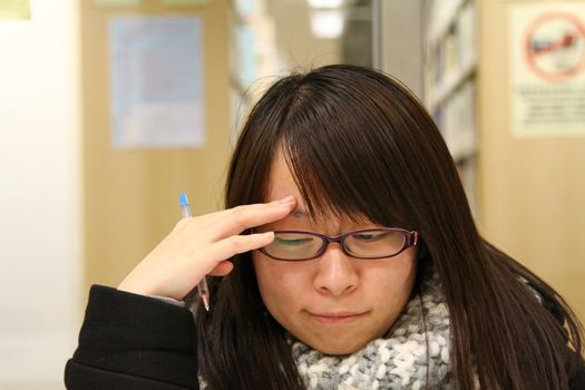 Asian woman thinking and studying in library