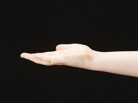 Childs hand with palm facing up - black background