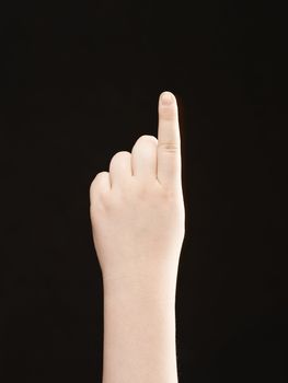 Childs hand with index finger pointing - on black background