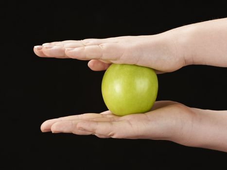 Childs hands with apple - on black background