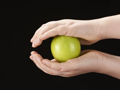 Childs hands with apple - on black background